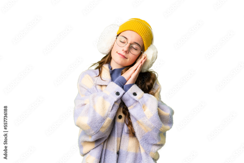 Teenager girl wearing winter muffs over isolated chroma key background making sleep gesture in dorable expression Teenager girl wearing winter muffs over isolated chroma key background making sleep gesture in dorable expression