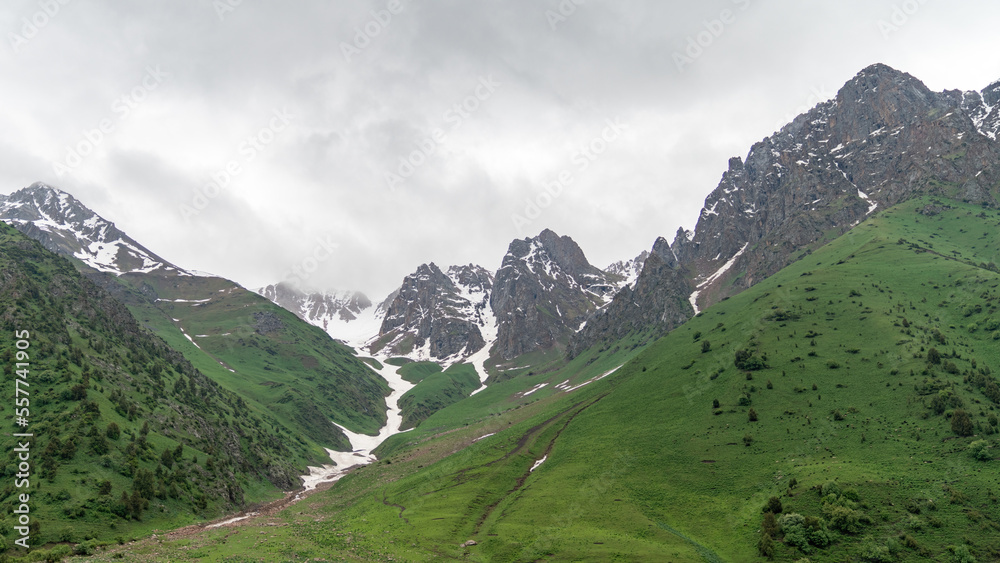 Kyrgyzstan nature green landscape with snow capped mountains. Kyrgyzstan is a landlocked country located in central Asia, known for its rugged, mountainous terrain and verdant grasslands.