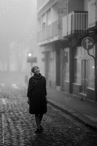 Obraz na płótnie A woman enjoys the atmosphere on the sidewalk in the thick fall morning fog. w salonie