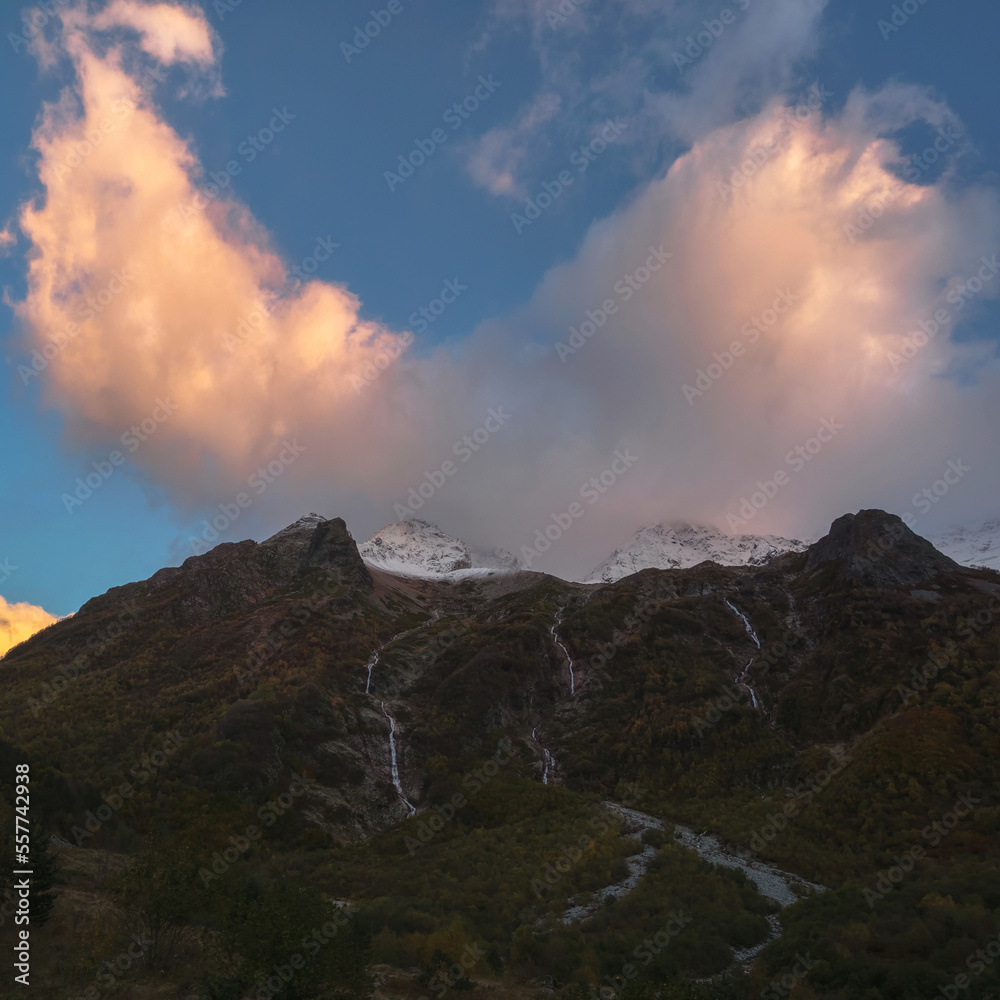 Colored cloud over the night mountains. Fiery cloud in the eveni