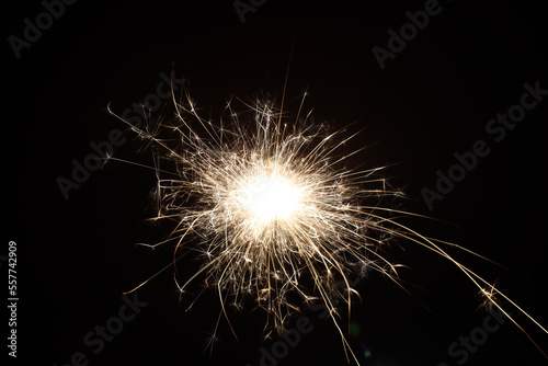 A single sparkler illuminates the darkness  its brilliant light shining like a star against the black background  the festive sparkler symbolizes joy and celebration.