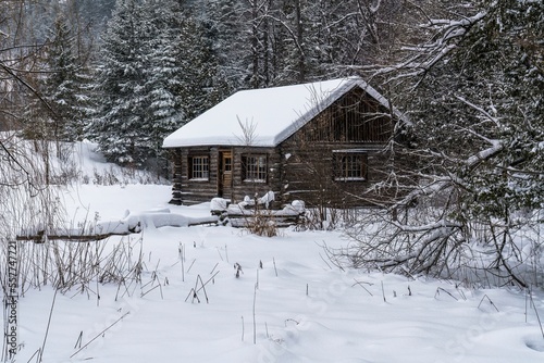 An old log cabin during winter snowfall in Wakefield, Quebec, Canada photo