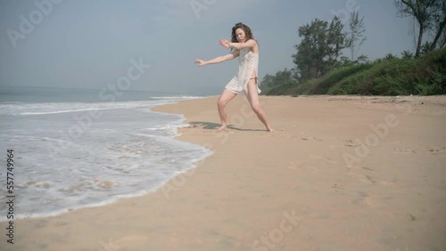 A beautiful white woman of European appearance, in a white dress, sexily dancing photo