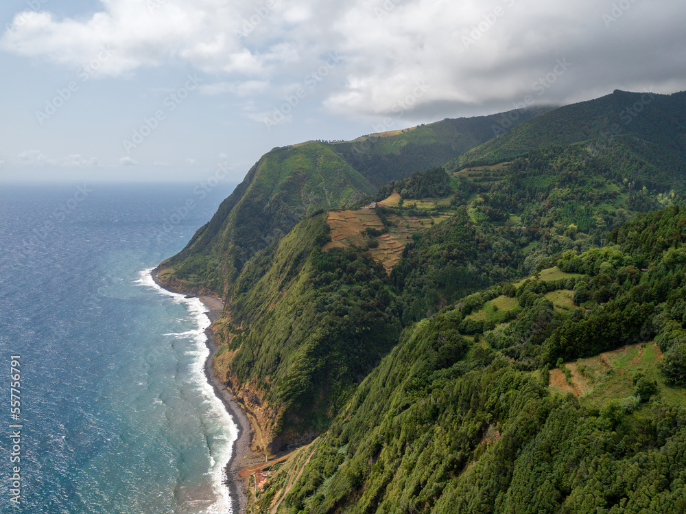 Amazing landscape on the northeast coast of the island of Sao Miguel in the Azores. Panoramic view of cliff with a path to the sea and a small fishing port. Tourist attraction of Portugal.