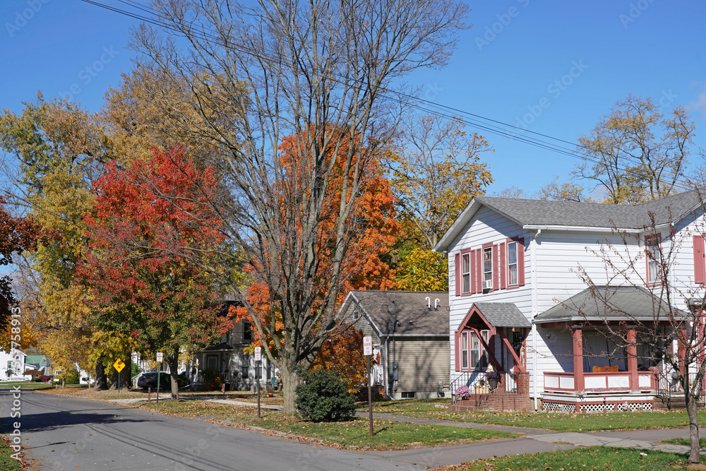 Small town residential street with white clapboard houses and trees with fall color