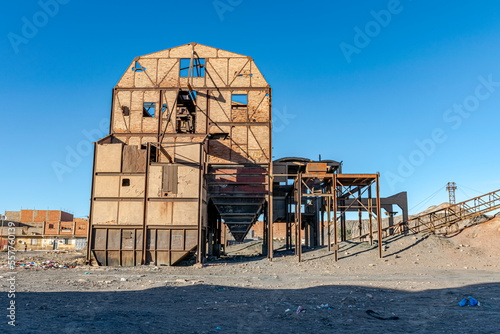 Old ruined coal preparation plant or coal handling in Kenadsa town, Bechar city, Algeria. Metallic structure remaining in a clear blue sky in background and dirt sandstones reg in foreground. photo