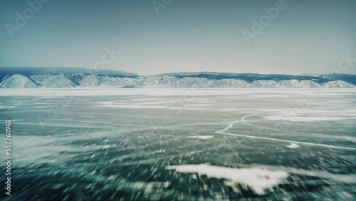 Fast flight over the ice of Lake Baikal, with a mountain range in the background. Olkhon Island, the Little Sea Strait. Baikal, Siberia, Russia. Drone aerial shot 4k photo