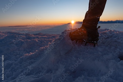 Man climbs a mountain peak in winter during sunrise. A shoe with spikes on - crampons. Sunrise on Babia Gora with a view of the Tatra Mountains photo