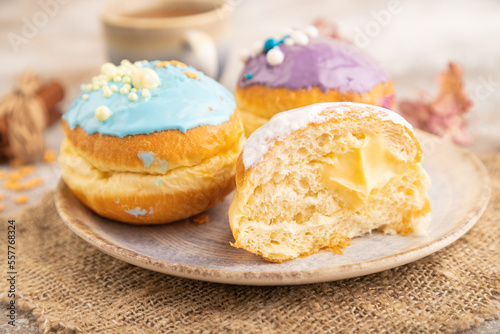 Purple and blue glazed donut and cup of coffee on brown concrete, side view, selective focus.