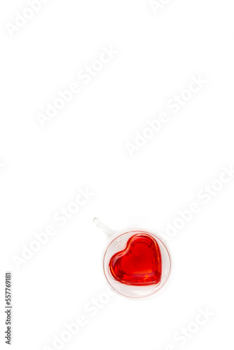 A transparent heart-shaped cup with tea on the white background, flat lay. © puhimec