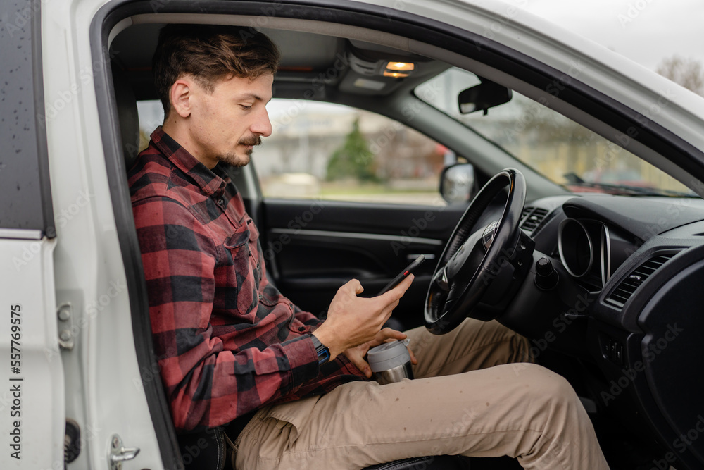 man hold cup with coffee use mobile phone sit in the car take a brake