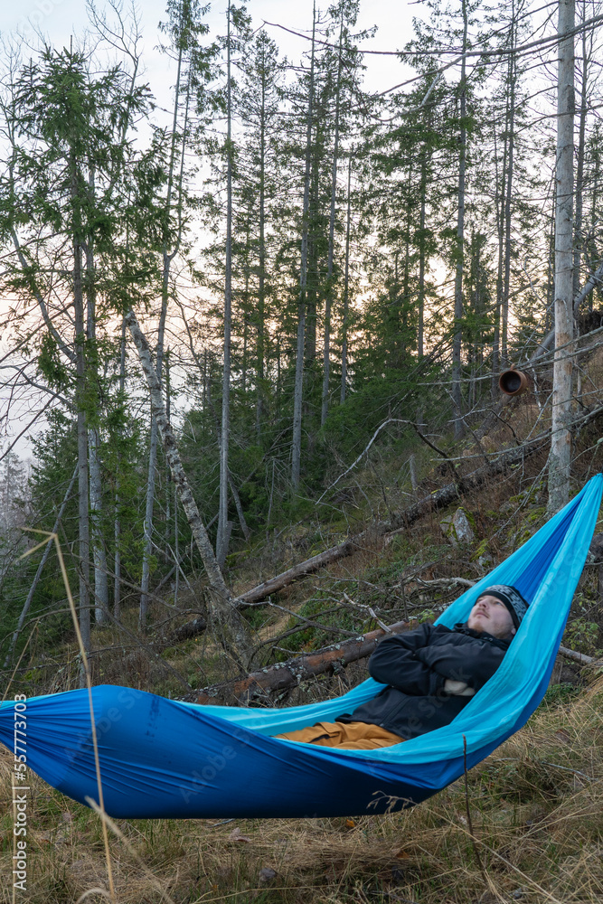 Fototapeta premium Hiker laying in a hammock between trees.