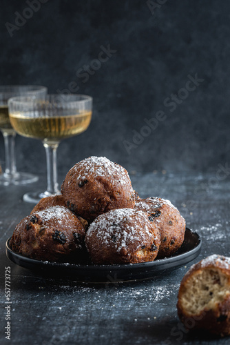 A stack of traditional oliebollen (translation: Dutch dough fritters) with a glass of champagne on black background