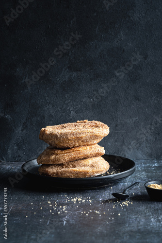 A stack of three apple beignets (apple fritters) on black background, no people