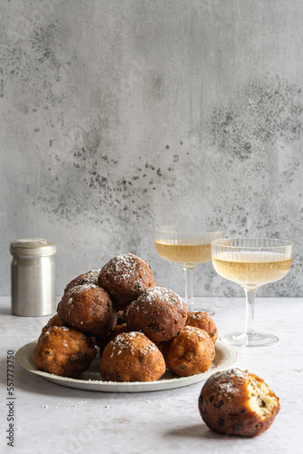 A stack of traditional oliebollen (translation: Dutch dough fritters) with a glass of champagne on white background