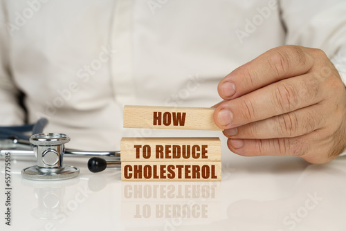 On a white surface, a stethoscope and wooden plates with the inscription - How to Reduce Cholesterol photo