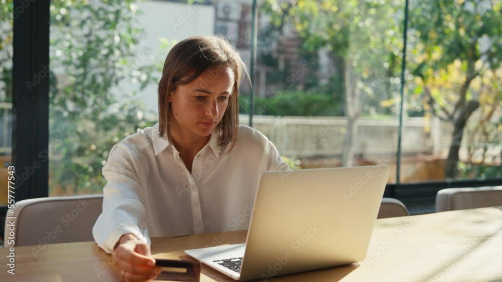 Young woman holding credit card and using laptop computer. Businesswoman working at home. Online shopping, e-commerce, internet banking, spending money, working from home concept Young woman holding credit card and using laptop computer. Businesswoman working at home. Online shopping, e-commerce, internet banking, spending money, working from home concept
