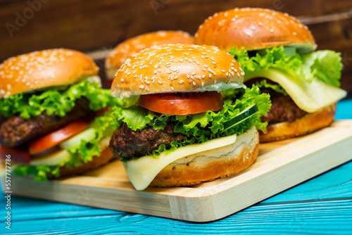 Homemade hamburgers with meat, cheese, lettuce, tomato on a wooden table