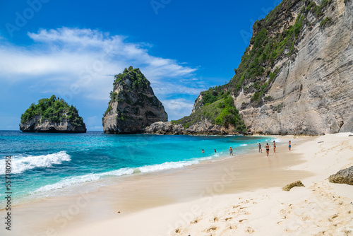 BALI / INDONESIA - NOVEMBER 8, 2022: People swimming at the beautiful sandy beach (Diamond beach) with rocky mountains and clear water in Nusa Penida. © umike_foto