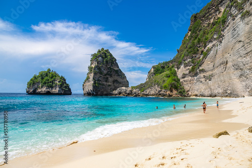 BALI   INDONESIA - NOVEMBER 8  2022  People swimming at the beautiful sandy beach  Diamond beach  with rocky mountains and clear water in Nusa Penida.