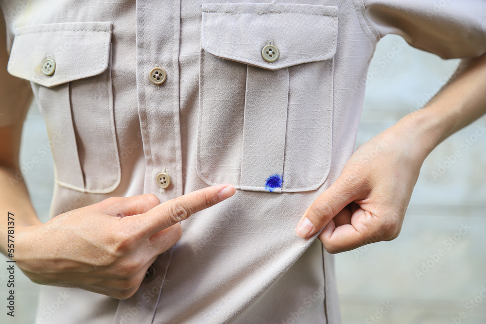 Hand showing dirty blue ink stain on shirt from accident in using pen in daily life. selective focus. stain for cleaning concept. Hand showing dirty blue ink stain on shirt from accident in using pen in daily life. selective focus. stain for cleaning concept.