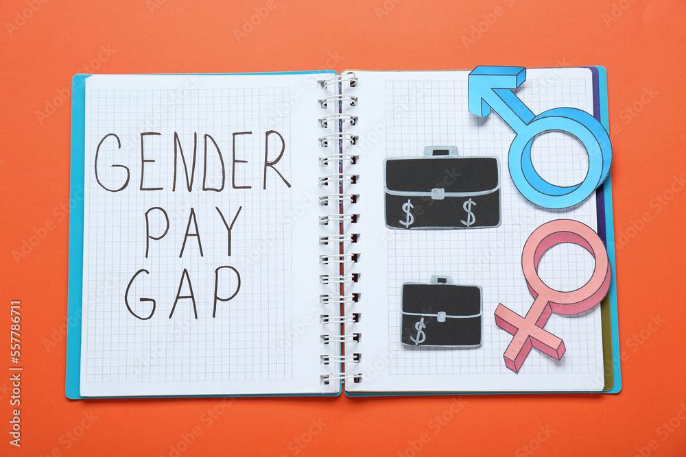 Gender pay gap. Notebook, paper briefcases with male and female symbols on orange background, top view Gender pay gap. Notebook, paper briefcases with male and female symbols on orange background, top view