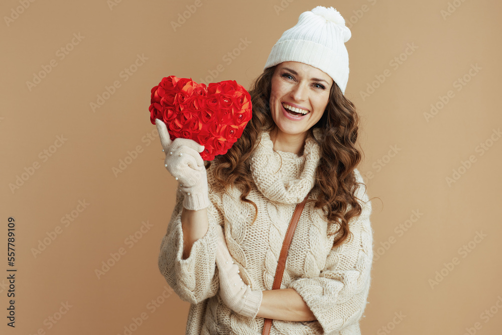 happy woman in beige sweater, mittens and hat against beige happy woman in beige sweater, mittens and hat against beige