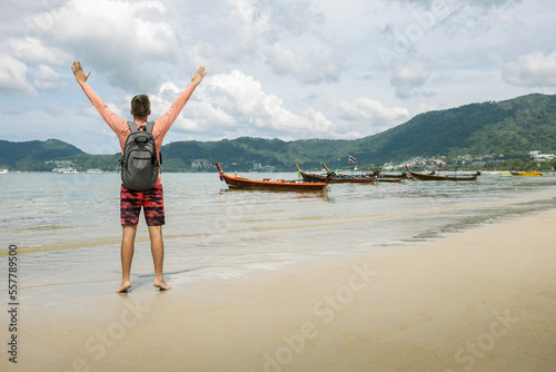 Happy man arms outstretched by the sea enjoying freedom and life, people travel vacation holiday concept photo