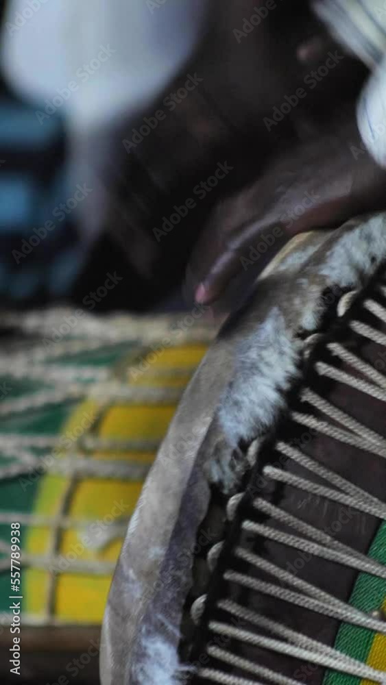 Vertical video of Black man in colorful clothes standing playing djembe Vertical video of Black man in colorful clothes standing playing djembe