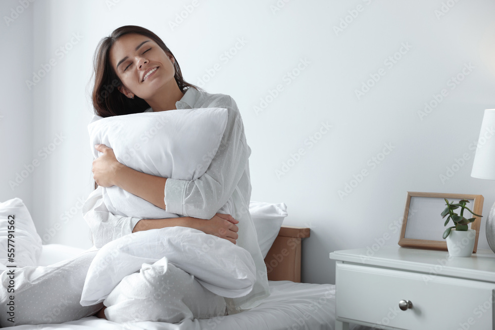 Beautiful young woman hugging pillow on bed at home Beautiful young woman hugging pillow on bed at home