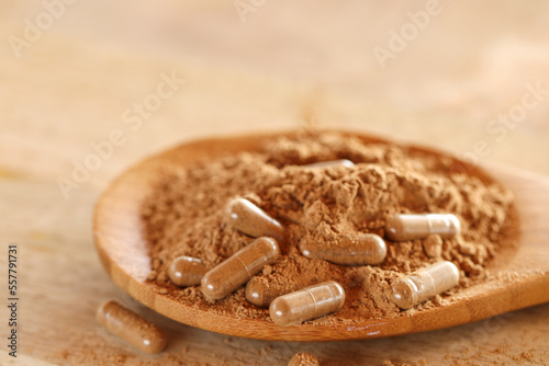 Guarana capsules in powder in a wooden spoon on a wooden table.Supplements and vitamins. Healthy eating. sports nutrition.Transparent capsules with guarana powder.Alternative medicine