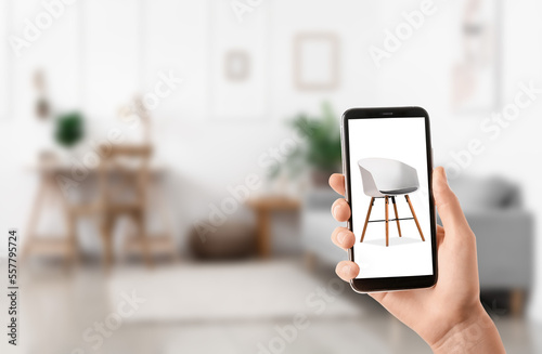 Woman with mobile phone buying online new chair in furniture store at home