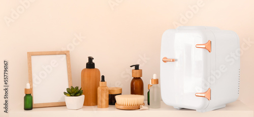 Shelf with small refrigerator and cosmetic products near light wall