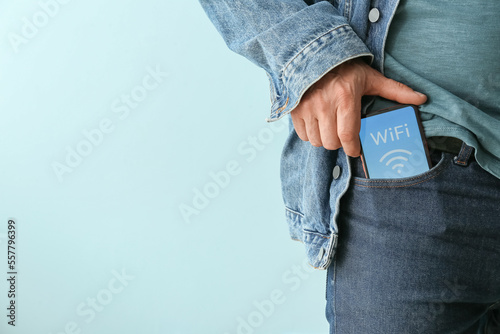 Man putting mobile phone with WiFi symbol into pocket, closeup