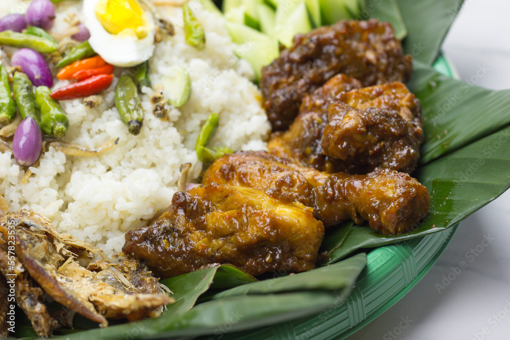 selective focus of Ayam bakar or grilled chicken served with nasi liwet A traditional Sundanese rice dish of white rice cooked with spices and topped
