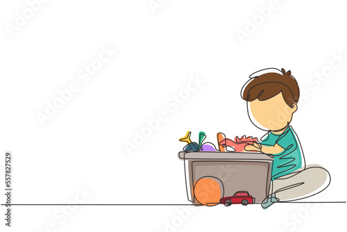 Single continuous line drawing little boy putting his toys into box. Kids doing housework chores at home concept. Smiling child storing his toys in the box. Dynamic one line draw graphic design vector