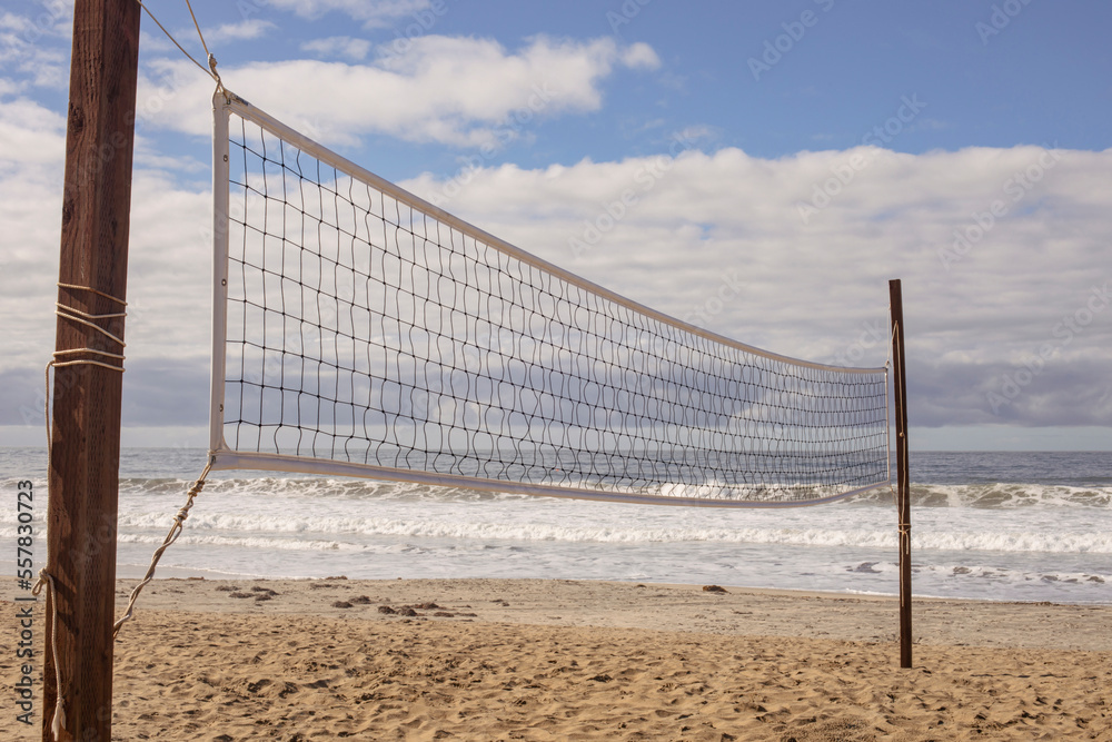 Beach volleyball net with the ocean and white clouds