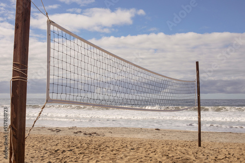 Beach volleyball net with the ocean and white clouds
