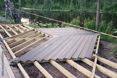 Walking area on screw piles, wooden frame, plastic terrace board, construction work in progress, landscape design