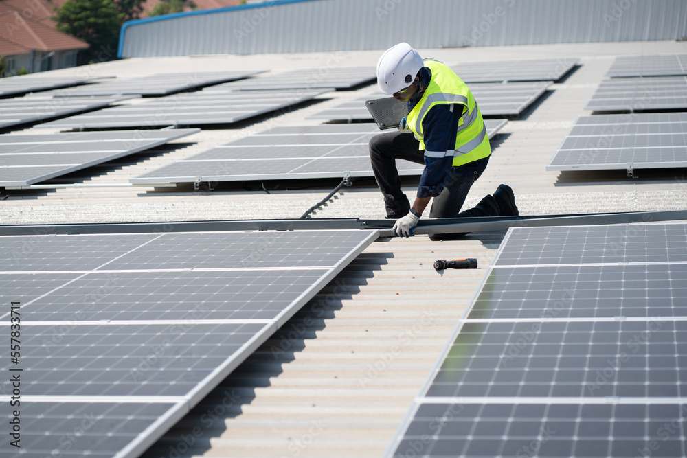 African American engineer man use electric screwdriver and computer notebook working with solar panel on roof factory African American engineer man use electric screwdriver and computer notebook working with solar panel on roof factory