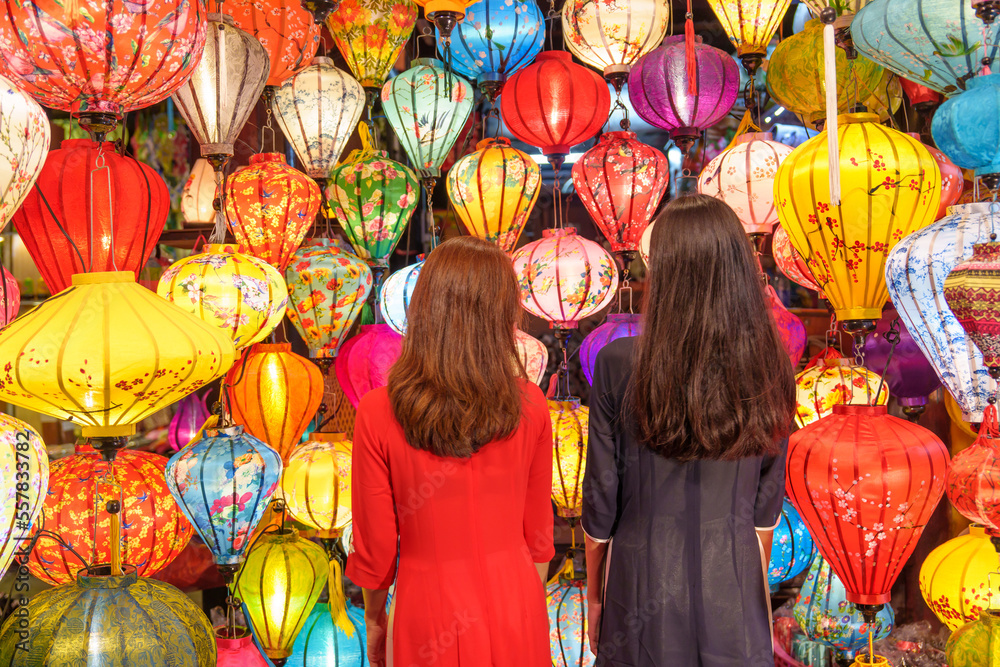 Couple women wearing Ao Dai Vietnamese dress with colorful lantern, traveler sightseeing at Hoi An ancient town in central Vietnam.landmark for tourist attractions.Vietnam and Southeast travel concept