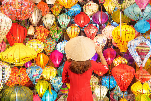 happy woman wearing Ao Dai Vietnamese dress with colorful lanterns  traveler sightseeing at Hoi An ancient town in central Vietnam.landmark for tourist attractions.Vietnam and Southeast travel concept