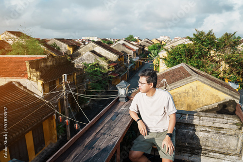 happy traveler traveling at Hoi An ancient town in Vietnam, man sightseeing view at rooftop. landmark and popular for tourist attractions. Vietnam and Southeast Asia travel concept