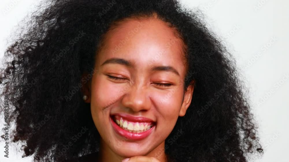 Slow motion. Looking at camera. Beautiful portrait african american girl with clean healthy skin and afro hairstyle smiling isolated on white studio background. Slow motion. Looking at camera. Beautiful portrait african american girl with clean healthy skin and afro hairstyle smiling isolated on white studio background.