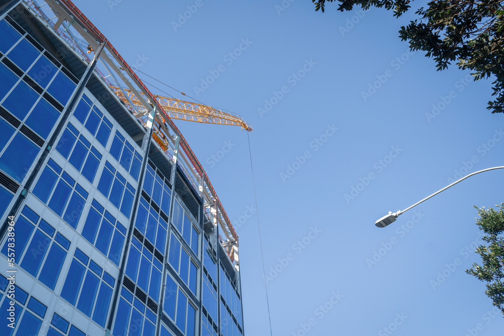Apartment under construction. Construction crane above the building against the bright blue sky. Auckland.