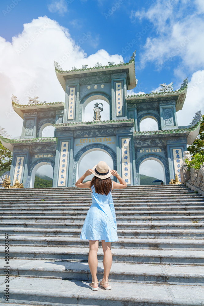 Woman traveler visiting at Linh Ung Pagoda temple, translation from Chinese character. Tourist with blue dress and hat traveling in Da Nang city. Vietnam and Southeast Asia travel concept