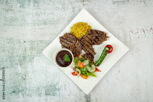 Set of grilled steaks on a black stone table with spices and herbs. Top view. Free space for your text.