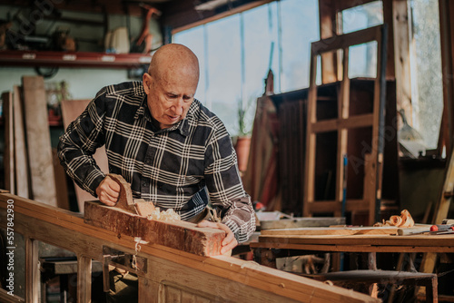 Senior carpenter using jointer in workshop photo