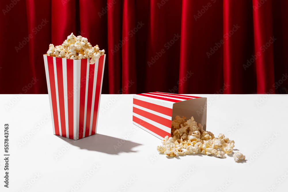 Two boxes of popcorn on a theater stage with red curtains