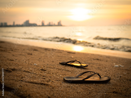 Sandals Tourism Woman on Sand Beach with Over Light Sunset Background at Coast,Flip Flops with Water Shore Nature in Dusk Golden Light,for Vacation Travel in Tropical Summer Holidays or Broken Heart.